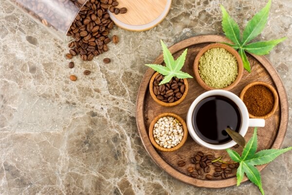 cup-aromatic-coffee-with-cannabis-marijuana-seeds-leaves-round-wooden-tray-scattered-coffee-beans-from-glass-jar-top-view