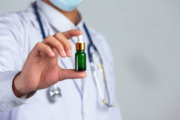 close-up-picture-medical-doctor-holding-bottle-cannabis-oil-white-wall