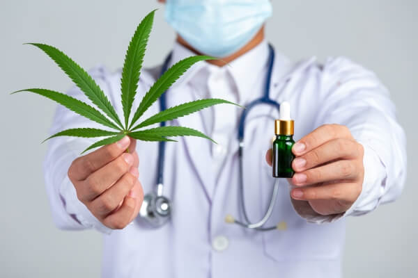 medical-doctor-holding-cannabis-leaf-bottle-cannabis-oil-white-wall